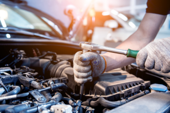 A photo of a person performing engine maintenance on a car. 