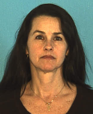 White lady with long dark hair posing for a headshot with blue background