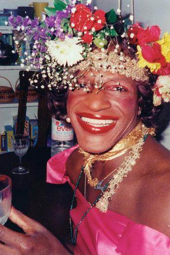 A candid photo of Marsha smiling, wearing a pink dress and elaborate flower crown.