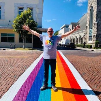 2015: Terry Fleming, late president of PCCNCF, made efforts to establish rainbow crosswalks throughout Gainesville with the city's Art in Crosswalks program. Here he stands on the crosswalk of NE 1st Street. Terry Fleming, late president of PCCNCF, stands on the Rainbow Crosswalk of NE 1st Street in Gainesville, FL.
