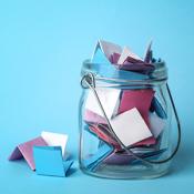 A clear jar holds colorful folded paper with a blue background.