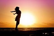 Woman's silhouette standing with arms wide in front of a setting sun