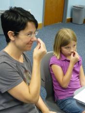 Mom and daughter signing flower with closed "o" hand near their noses